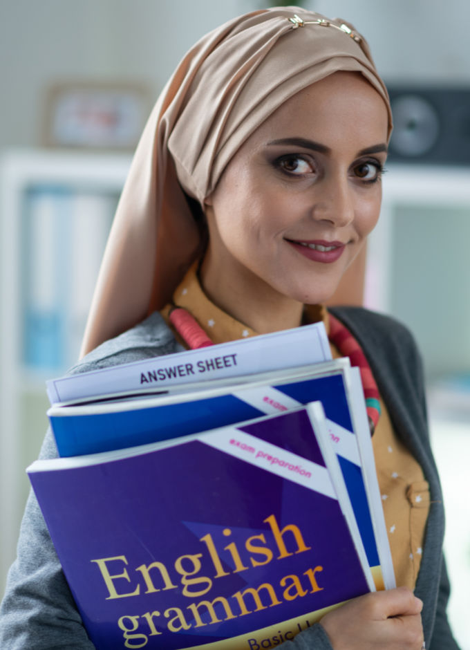 A young lady with head scarf holding English grammar book